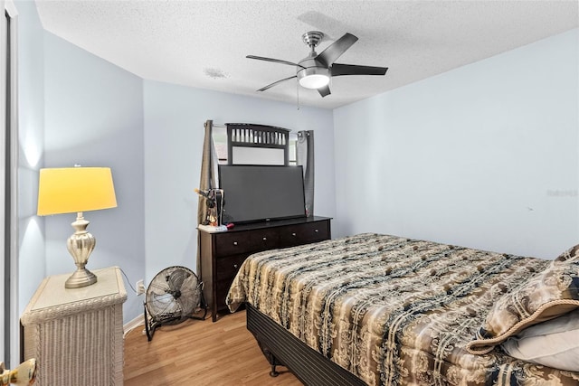 bedroom with a textured ceiling, ceiling fan, and light hardwood / wood-style floors