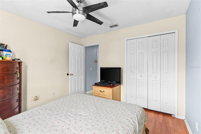 bedroom featuring ceiling fan, a textured ceiling, a closet, and light wood-type flooring