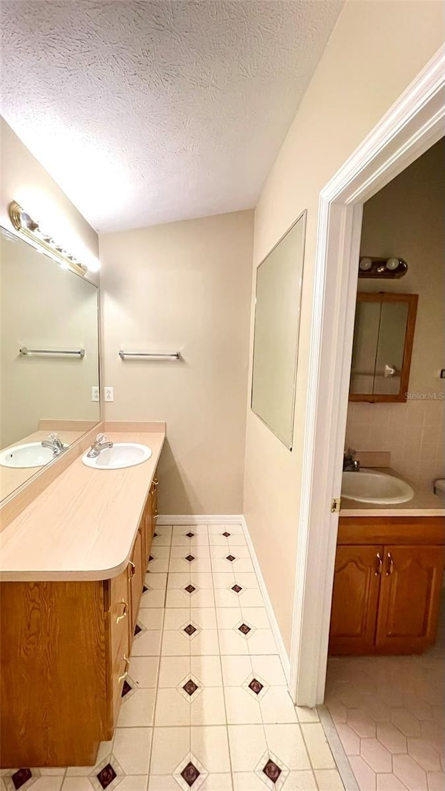 bathroom featuring tile patterned flooring, vanity, and a textured ceiling