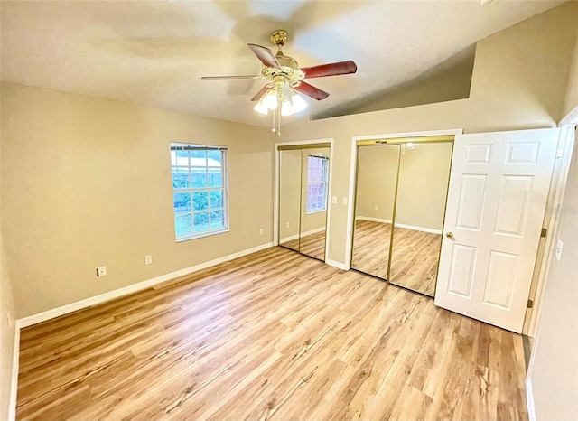 unfurnished bedroom with light hardwood / wood-style floors, ceiling fan, and multiple closets