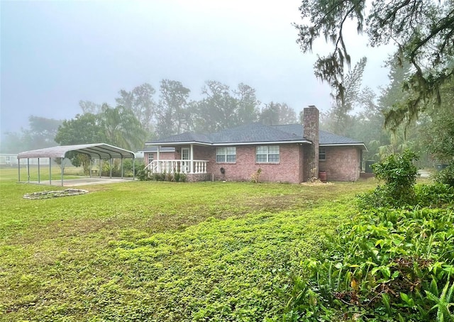 back of property with a carport and a lawn