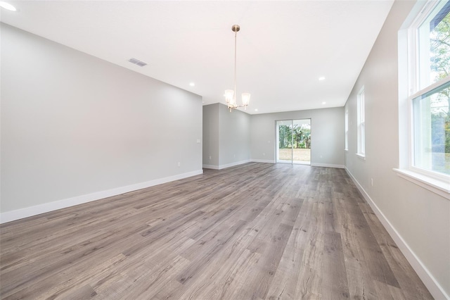 spare room featuring a notable chandelier and light hardwood / wood-style flooring