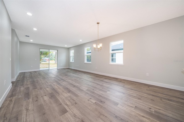 spare room with light hardwood / wood-style floors and a notable chandelier