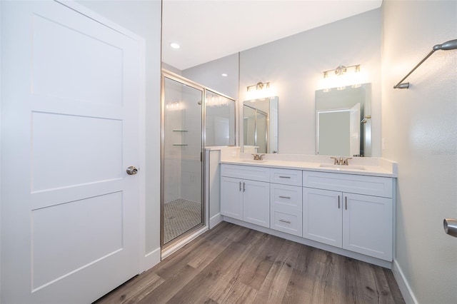 bathroom with wood-type flooring, vanity, and a shower with shower door