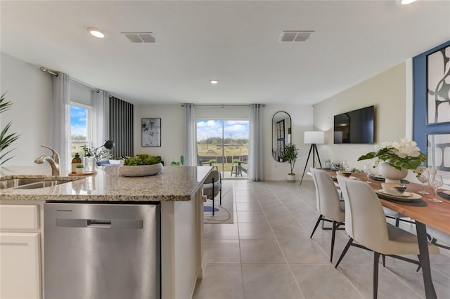 kitchen with light stone countertops, dishwasher, sink, plenty of natural light, and white cabinets