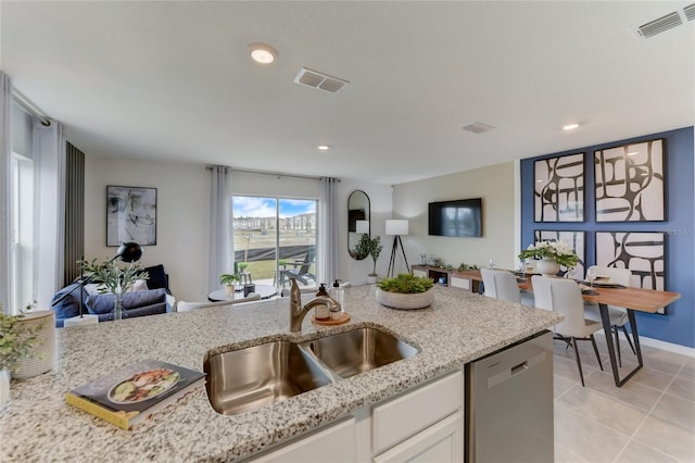 kitchen featuring light stone counters, stainless steel dishwasher, sink, light tile patterned floors, and white cabinets