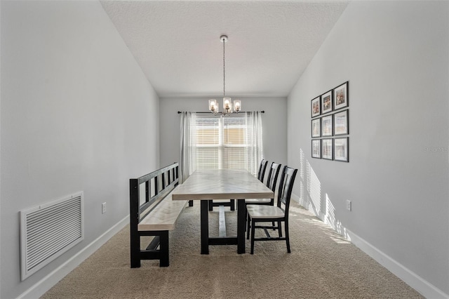 dining area with carpet flooring, a textured ceiling, and an inviting chandelier