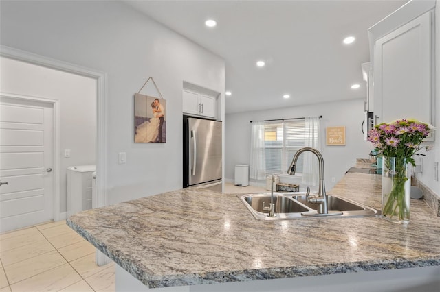 kitchen featuring white cabinets, stainless steel fridge, kitchen peninsula, and sink