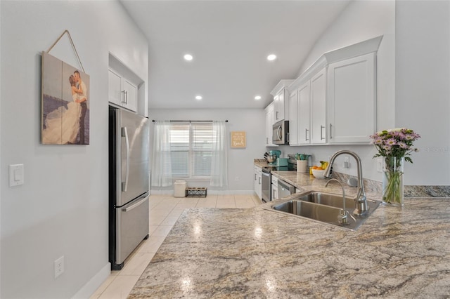 kitchen featuring sink, light stone countertops, light tile patterned floors, appliances with stainless steel finishes, and white cabinetry