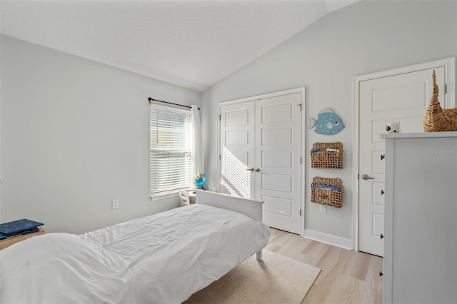 bedroom featuring vaulted ceiling, a closet, and light hardwood / wood-style flooring