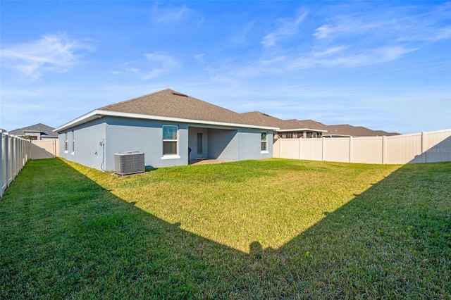 rear view of property with central AC unit and a yard