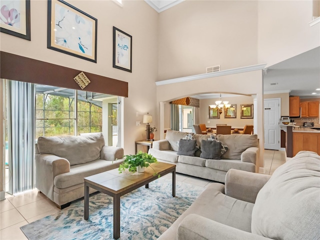 living room featuring a notable chandelier, light tile patterned flooring, a high ceiling, and ornamental molding