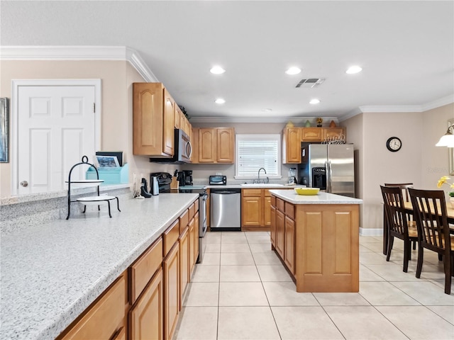 kitchen featuring light stone counters, appliances with stainless steel finishes, crown molding, and a kitchen island