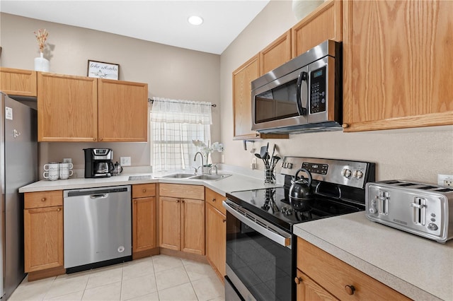 kitchen with appliances with stainless steel finishes, sink, and light tile patterned flooring