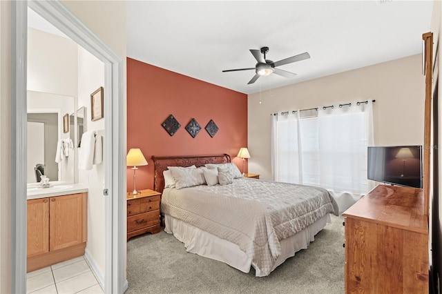 bedroom with ceiling fan, light colored carpet, sink, and ensuite bathroom