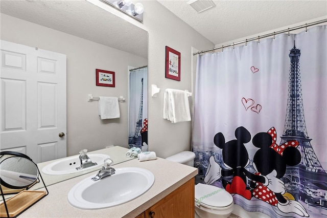 bathroom with toilet, vanity, and a textured ceiling