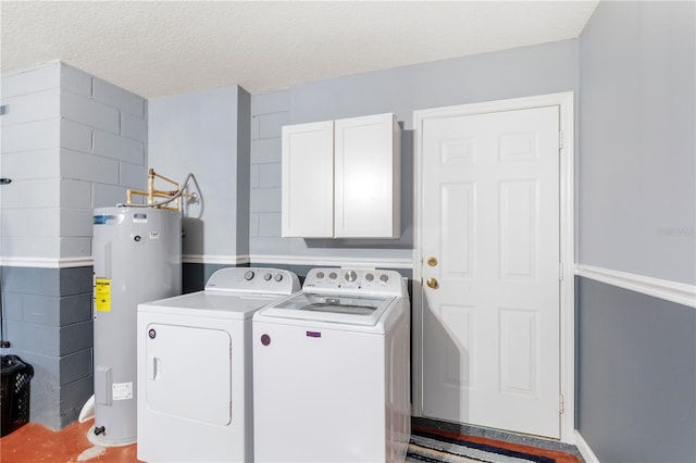 clothes washing area with washer and clothes dryer, water heater, a textured ceiling, and cabinets