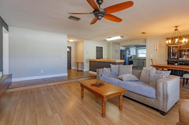 living room with light hardwood / wood-style flooring and ceiling fan with notable chandelier