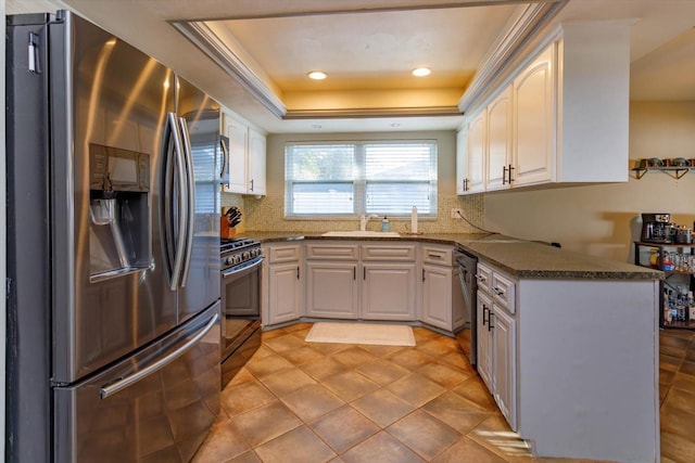 kitchen with kitchen peninsula, stainless steel appliances, white cabinets, and a tray ceiling