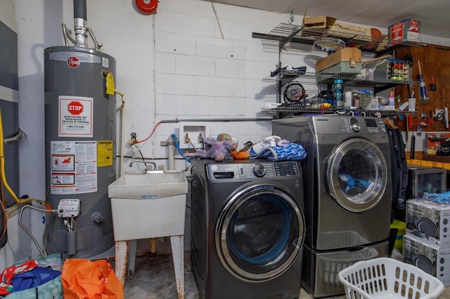 clothes washing area with gas water heater, washer and clothes dryer, and sink