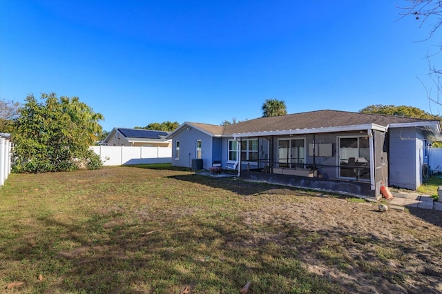 rear view of property featuring a sunroom and a yard