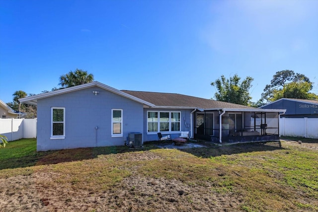 rear view of property featuring central air condition unit, a lawn, and a sunroom