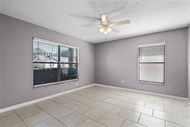 spare room with a textured ceiling, ceiling fan, and light tile patterned floors