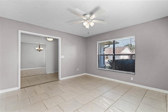 tiled empty room with a textured ceiling and ceiling fan with notable chandelier