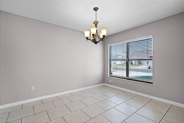 tiled empty room with a textured ceiling and a notable chandelier