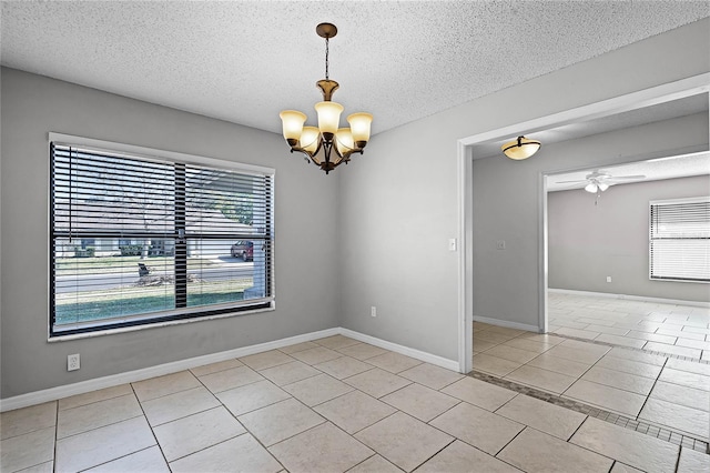 tiled empty room featuring ceiling fan with notable chandelier and a textured ceiling