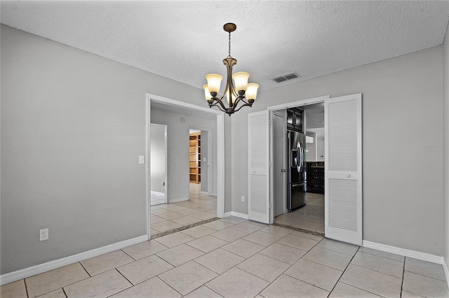 unfurnished dining area with a textured ceiling, an inviting chandelier, and light tile patterned floors