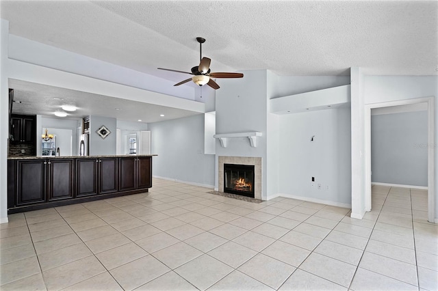 unfurnished living room with lofted ceiling, a tile fireplace, ceiling fan, and light tile patterned floors