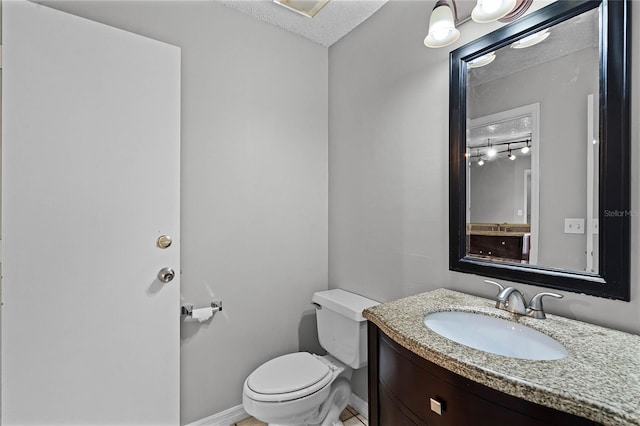 bathroom featuring toilet, vanity, and a textured ceiling