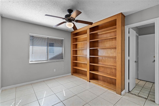 spare room featuring a textured ceiling, ceiling fan, and light tile patterned flooring