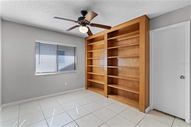 tiled spare room with built in shelves, a textured ceiling, and ceiling fan