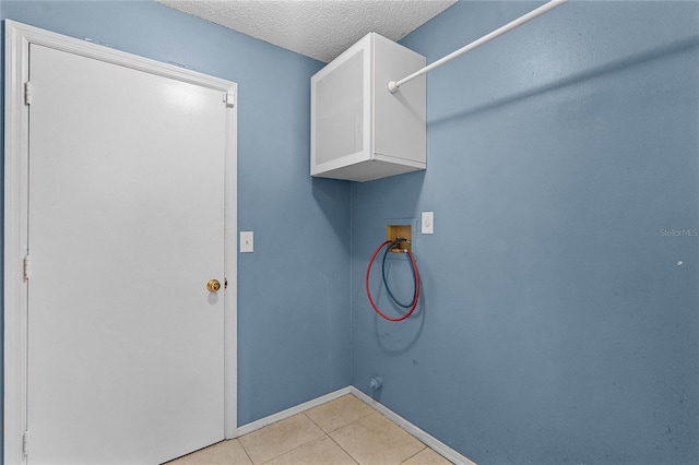 clothes washing area featuring hookup for a washing machine, a textured ceiling, cabinets, and light tile patterned flooring