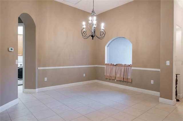 spare room featuring a notable chandelier, washer / clothes dryer, and light tile patterned flooring