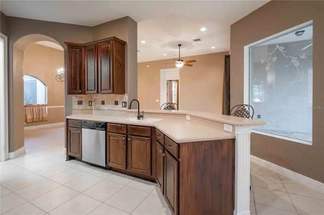 kitchen with light tile patterned flooring, tasteful backsplash, dishwasher, sink, and kitchen peninsula