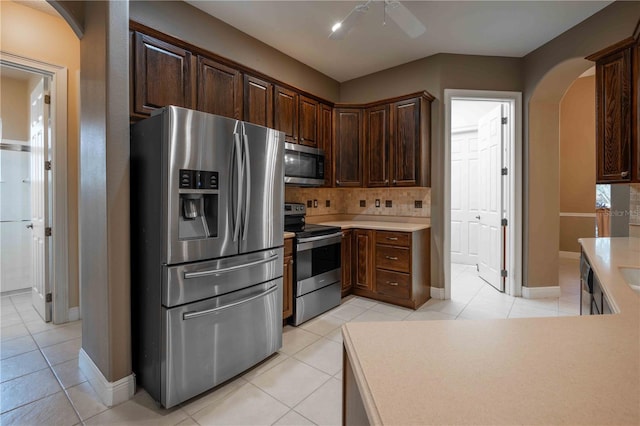 kitchen with appliances with stainless steel finishes, backsplash, light tile patterned floors, ceiling fan, and dark brown cabinets