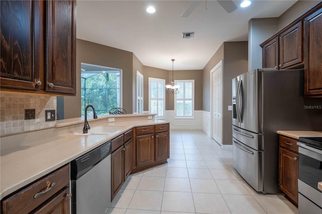 kitchen with sink, hanging light fixtures, light tile patterned floors, stainless steel appliances, and dark brown cabinets