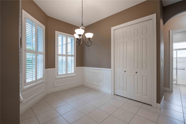 unfurnished dining area featuring light tile patterned flooring and a chandelier