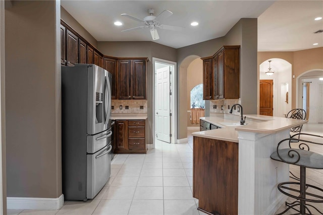 kitchen with sink, tasteful backsplash, stainless steel fridge, a kitchen breakfast bar, and kitchen peninsula