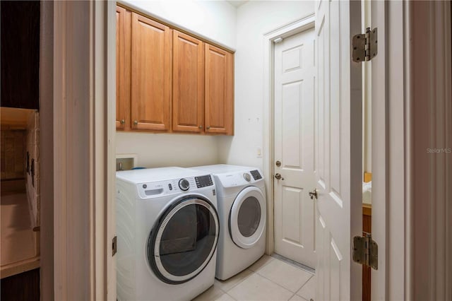 clothes washing area with cabinets, separate washer and dryer, and light tile patterned floors