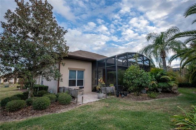 rear view of house featuring a lanai, a lawn, and a patio