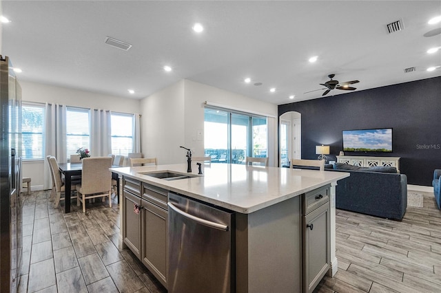 kitchen featuring gray cabinetry, a kitchen island with sink, sink, stainless steel dishwasher, and ceiling fan