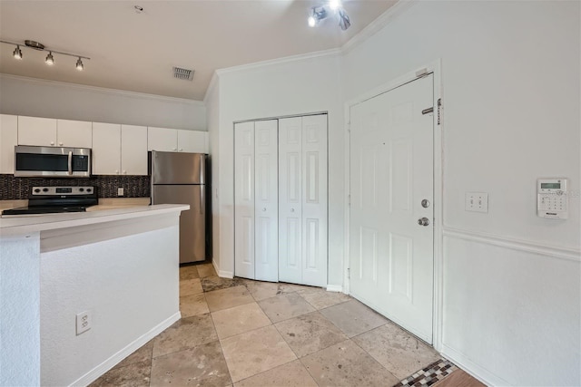 kitchen featuring backsplash, white cabinets, ornamental molding, and appliances with stainless steel finishes