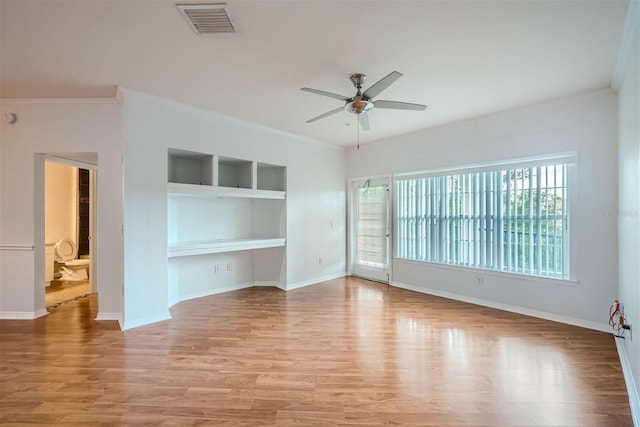 unfurnished living room with built in shelves, light wood-type flooring, ceiling fan, and ornamental molding