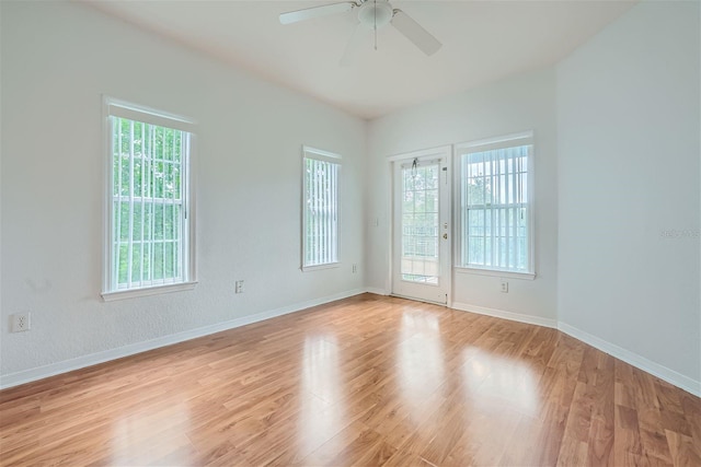 empty room featuring a wealth of natural light, ceiling fan, and light hardwood / wood-style flooring