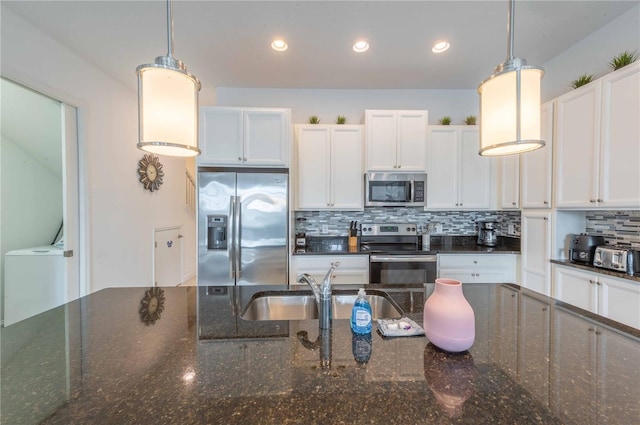 kitchen with pendant lighting, dark stone counters, appliances with stainless steel finishes, white cabinetry, and washer / clothes dryer