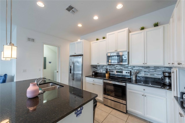 kitchen with tasteful backsplash, dark stone counters, stainless steel appliances, decorative light fixtures, and white cabinets